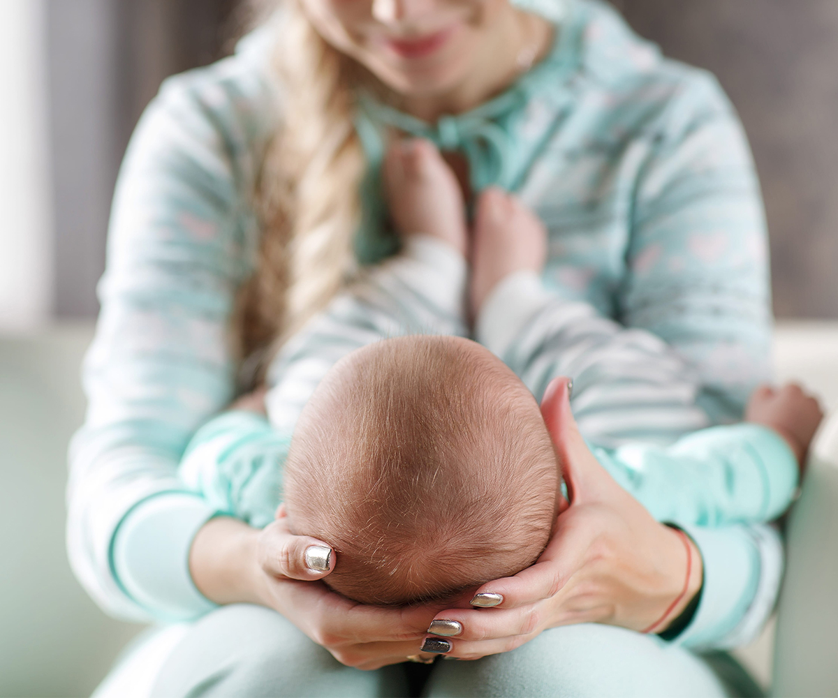 Baby resting against an adult’s shoulder during feeding or soothing